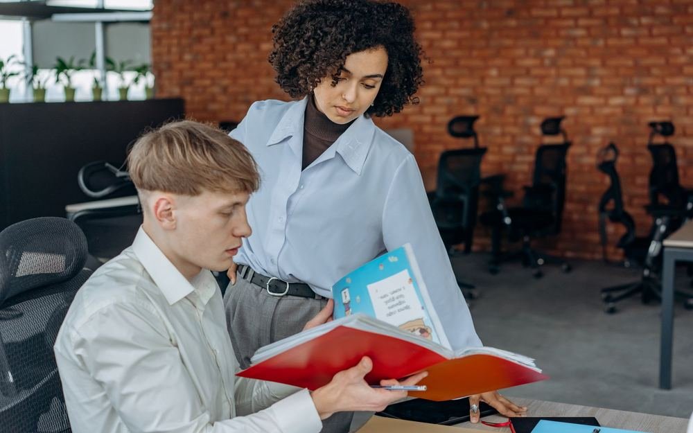 An apprentice and a colleague going through a folder of work