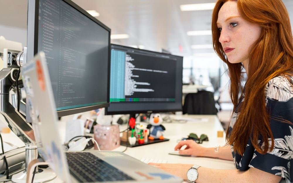 A developer working on code across two screens