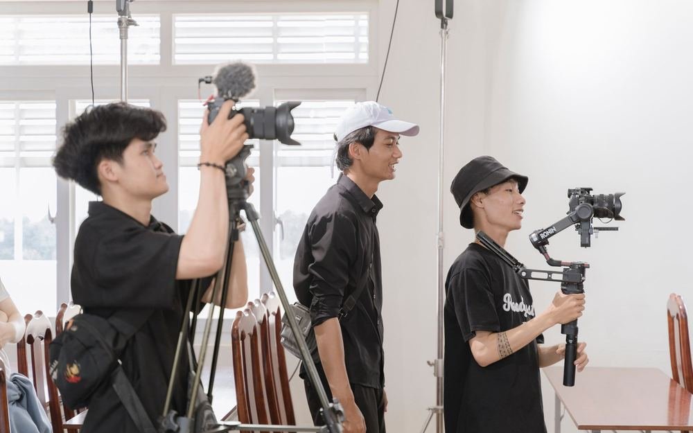 A small crew filming with a camera and a gimbal in a studio