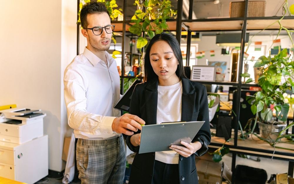Two colleagues reviewing work on a tablet in an open plan office